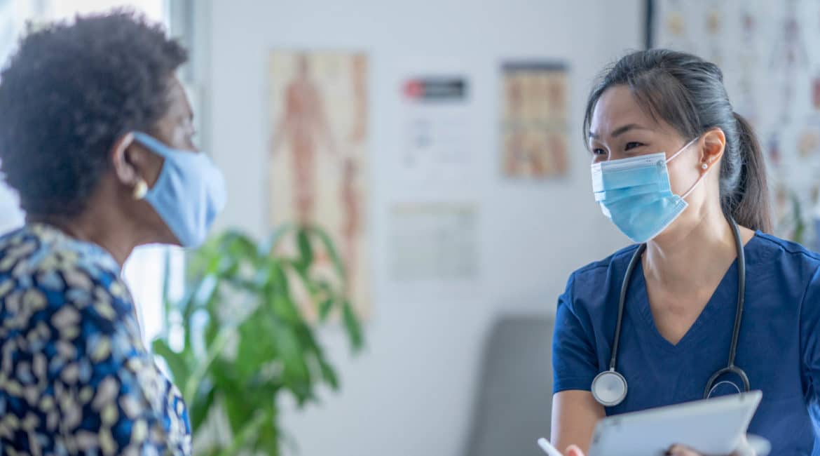 Doctor and patient in consult room in conversation with surgical masks on