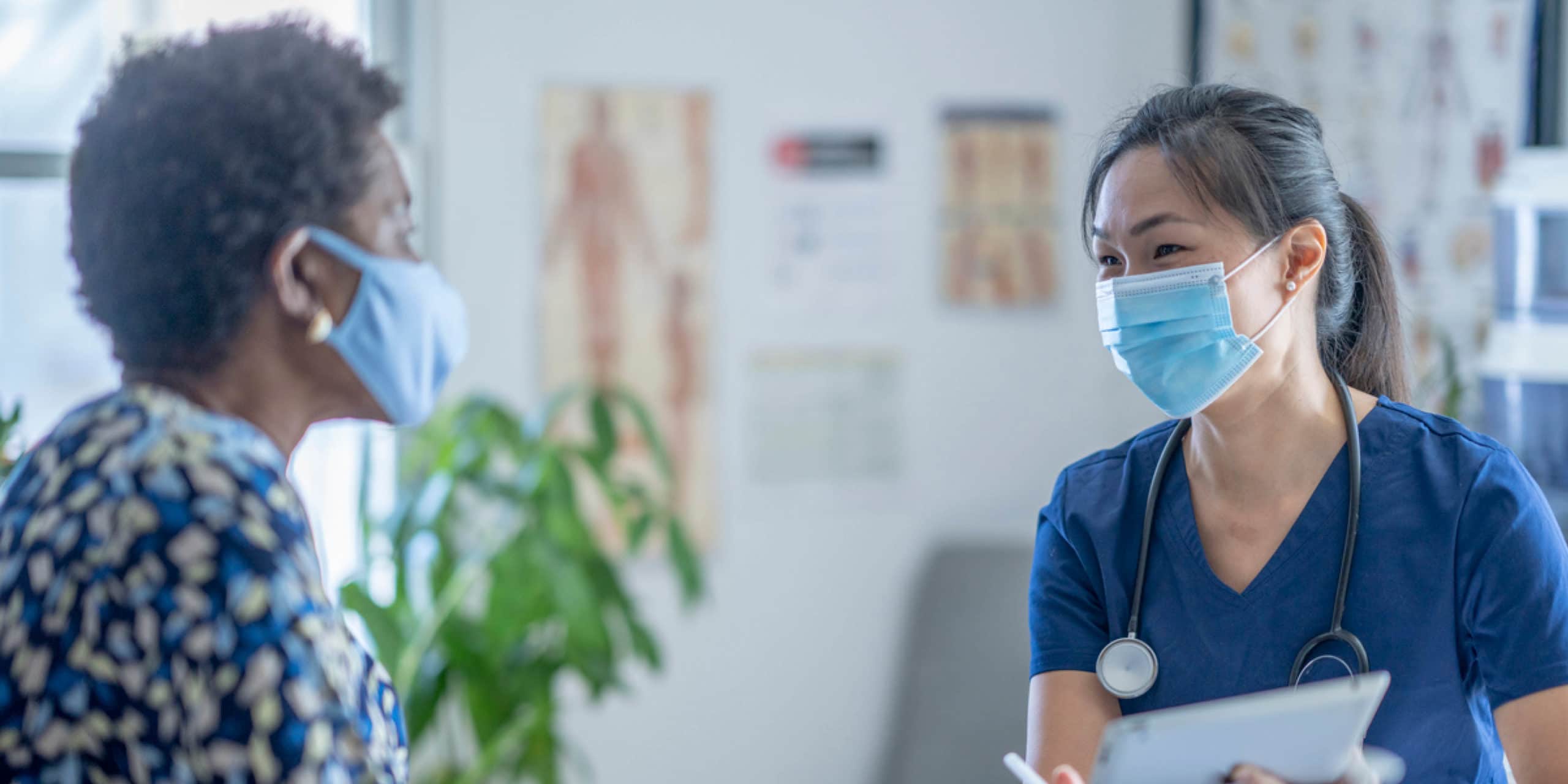 Doctor and patient in consult room in conversation with surgical masks on