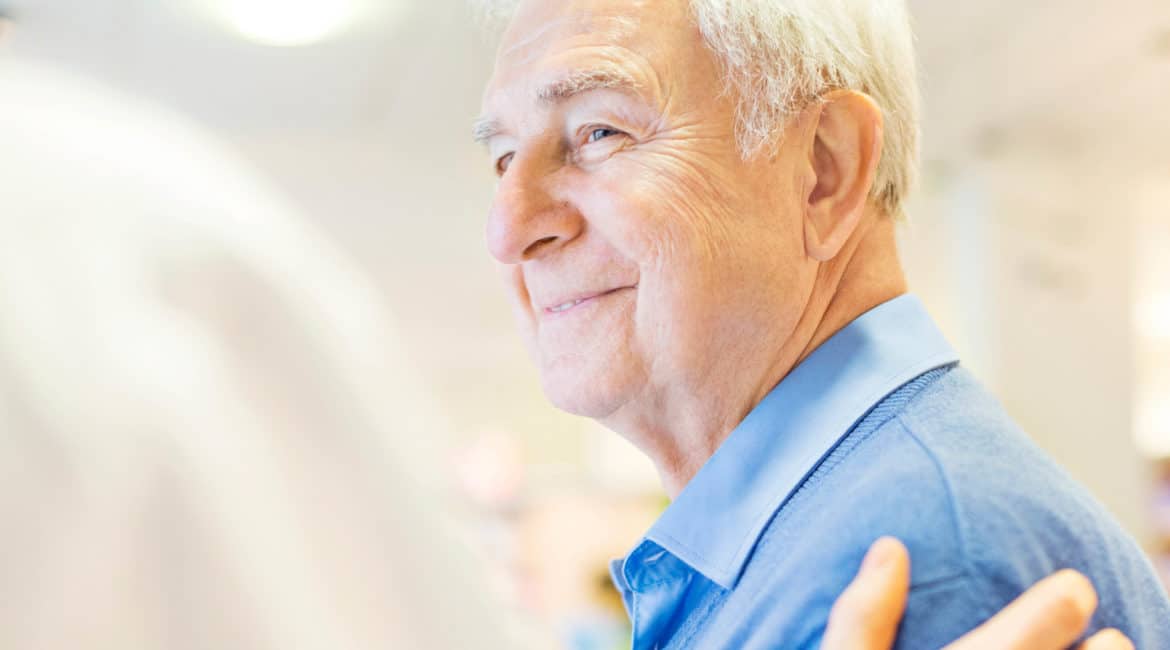 Elderly male patient smiling with the doctor's hand on their shoulder