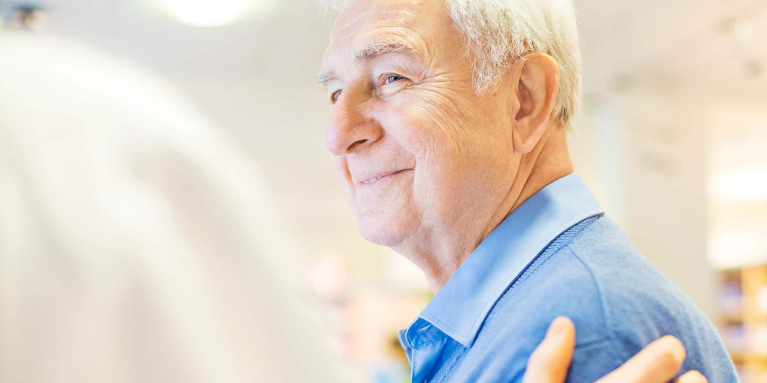 Elderly male patient smiling with the doctor's hand on their shoulder